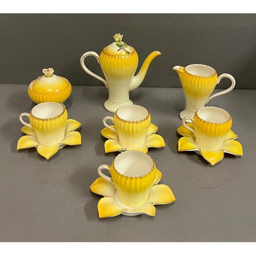 329 - A decorative coffee pot set, the porcelain China cups with rib sides and saucers in the form of flow... 