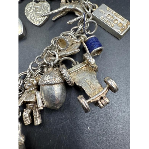 572 - A silver charm bracelet with a variety of charms, approximate weight 47g.