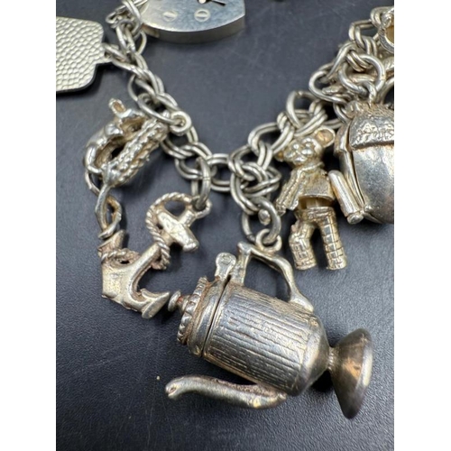 572 - A silver charm bracelet with a variety of charms, approximate weight 47g.