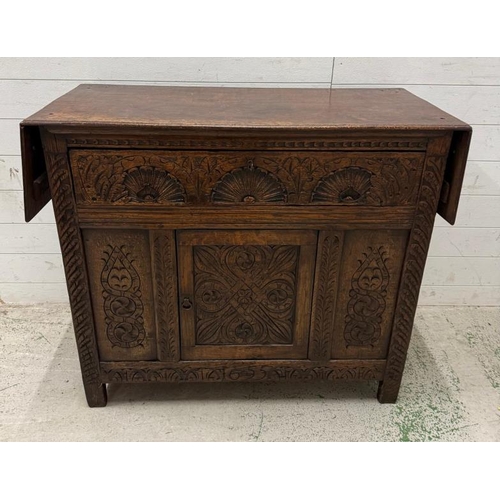 127 - An oak butlers companion or sideboard with heavily carved panels to front, comprising of single draw... 