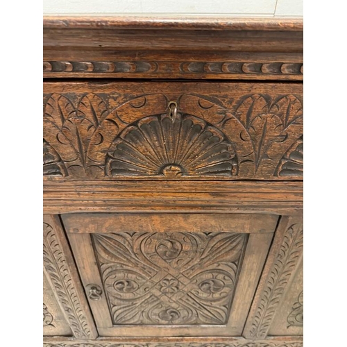 127 - An oak butlers companion or sideboard with heavily carved panels to front, comprising of single draw... 