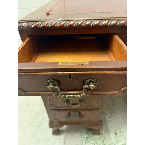 168 - A red leather topped pedestal desk, one long central drawer flanked by eight short drawers and on cl... 