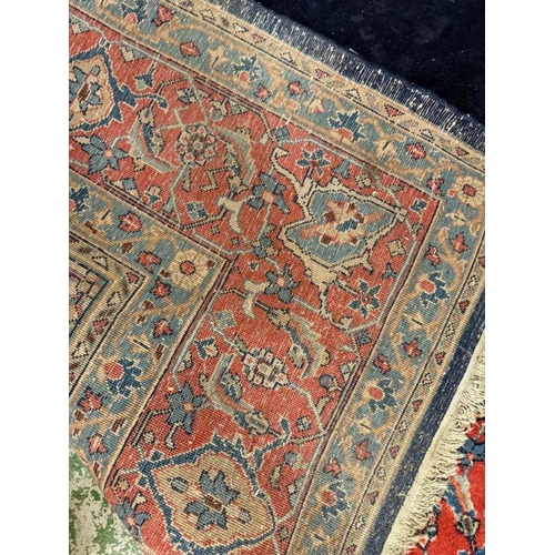 194 - A wool rug blue grounds with scrolling border and red central shield 340cm x 210cm