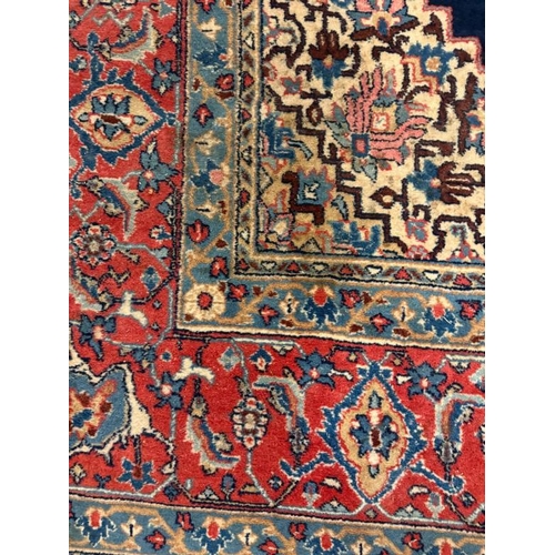 194 - A wool rug blue grounds with scrolling border and red central shield 340cm x 210cm