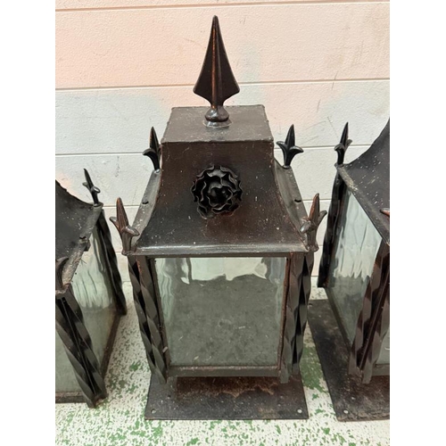 229 - Four wrought iron coach house wall mounted lanterns and one matching wall hanging lantern