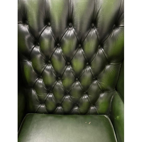 29 - A green faux leather wingback chair with a button-tufted back, cabriole legs and brass stud detailin... 