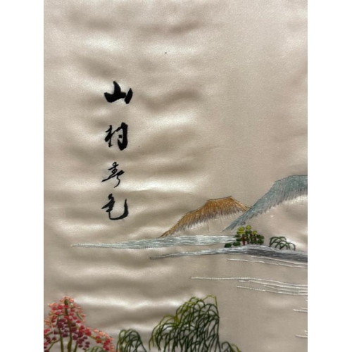 344 - A Japanese framed embroidered silk of a lakeside scene with mountains and a village to foreground, s... 