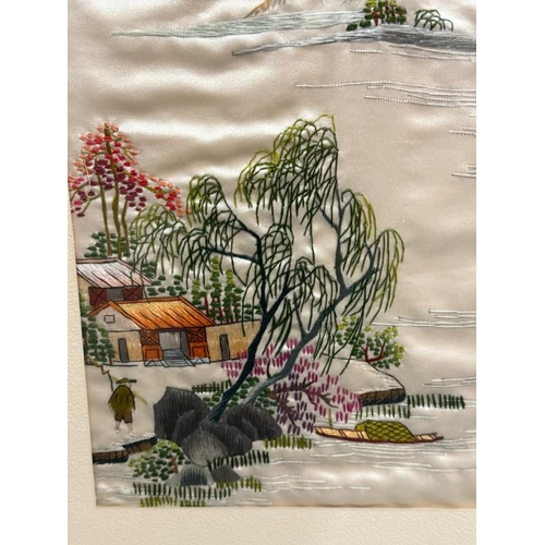 344 - A Japanese framed embroidered silk of a lakeside scene with mountains and a village to foreground, s... 