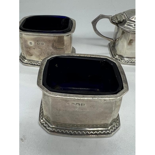 498 - A William Neale & Son silver cruet set to include a mustard, two salts with blue glass liners and tw... 