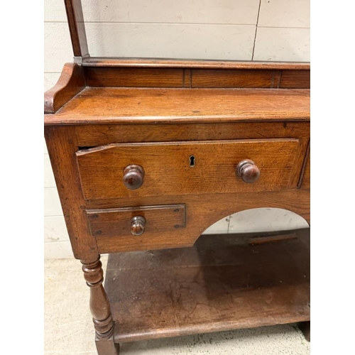 50 - A George III style oak dresser with three open shelves, the lower part with three short drawers rais... 