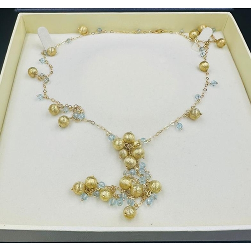 570 - An 18ct gold necklace with interspaced balls and aquamarine style stones and an approximate weight o... 