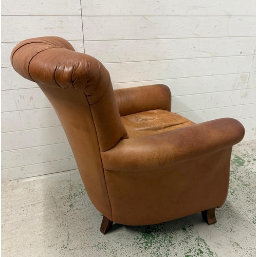 58 - A tan leather upholstered armchair with brass stud detail