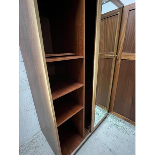 79 - An Ercol style double wardrobe, the sliding mirrored door moves to reveal shelves and hanging rail t... 