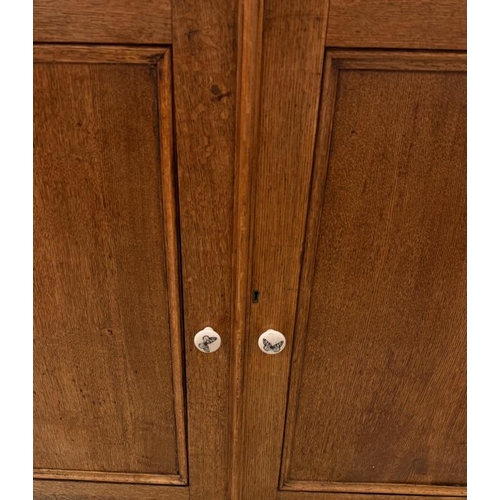 99 - A light oak linen press, the double panel doors opening to shelves upon base unit opening to linen p... 