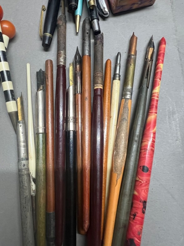 A collection of writing instruments including ink pens, roller ball ...