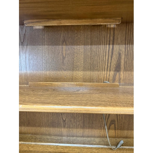 136 - An ercol mural wall unit in a golden dawn finish featuring an open bookcase over a two door cabinet ... 