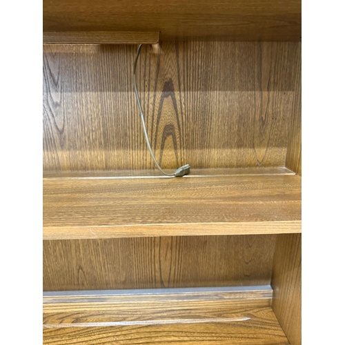 136 - An ercol mural wall unit in a golden dawn finish featuring an open bookcase over a two door cabinet ... 