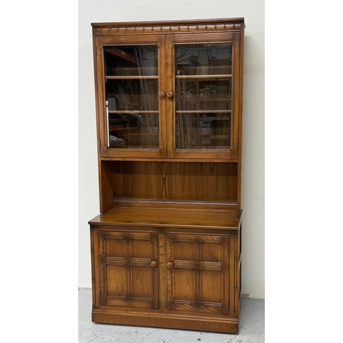 138 - An Ercol mural two-door display cabinet over a two-door cupboard H197cm W98cm D49