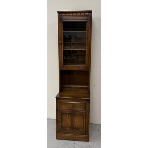 149 - A dark Ercol narrow bookcase or display cabinet, glazed and with a single drawer, single door unit u... 