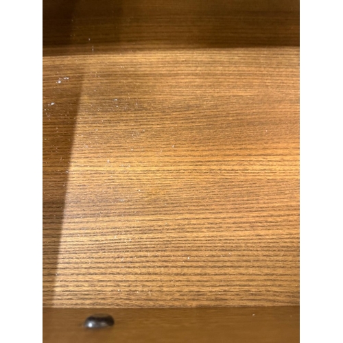 149 - A dark Ercol narrow bookcase or display cabinet, glazed and with a single drawer, single door unit u... 