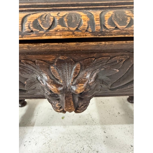 170 - A Belgian oak heavily carved writing table in the Henry II style with drawers flanked by lion head a... 