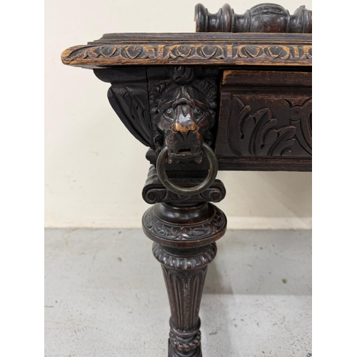 170 - A Belgian oak heavily carved writing table in the Henry II style with drawers flanked by lion head a... 