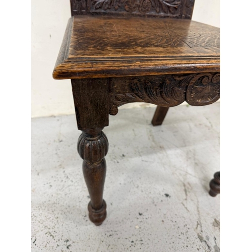 171 - An oak Jacobean-style hall chair with a heavily carved back ad on turned legs