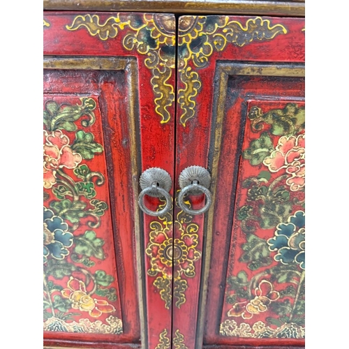 2 - A Chinese style hall cabinet with two cupboards, red grounds and decorated with green and gilt flowe... 