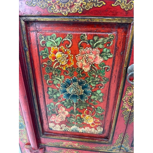 2 - A Chinese style hall cabinet with two cupboards, red grounds and decorated with green and gilt flowe... 