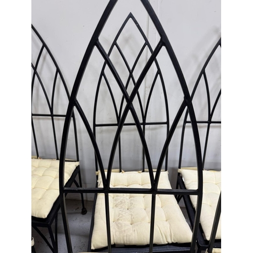 186 - A set of eight gothic revival wrought iron dinning chairs with arched backs an cream cushions. Heigh... 