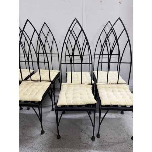 186 - A set of eight gothic revival wrought iron dinning chairs with arched backs an cream cushions. Heigh... 