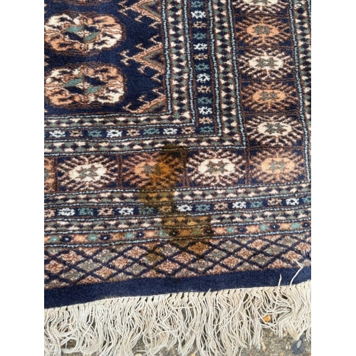 191 - A wool rug with blue ground, red and blue geometric boarder 168cm x 245cm