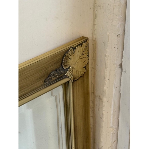 192 - A gold bevel edged over mantle mirror with fig leaf detail to corners Width 106cm x Height 76cm.
