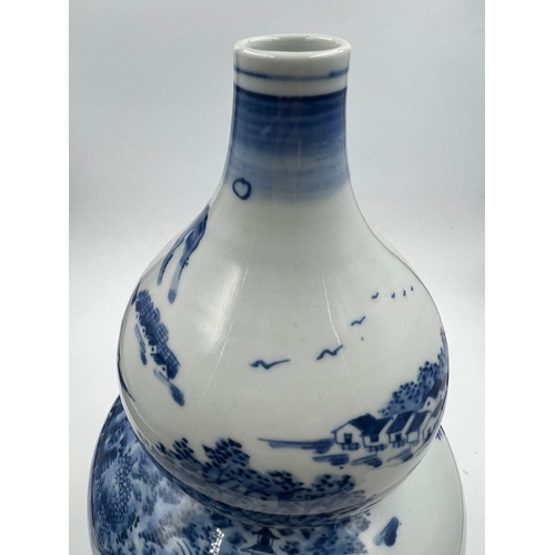 270 - A Japanese blue and white double gourd vase featuring a continuous landscaped scene, signed to base ... 