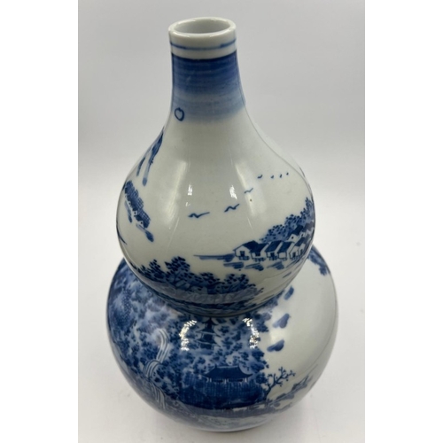 270 - A Japanese blue and white double gourd vase featuring a continuous landscaped scene, signed to base ... 