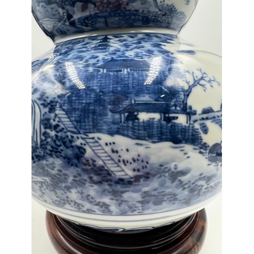 270 - A Japanese blue and white double gourd vase featuring a continuous landscaped scene, signed to base ... 