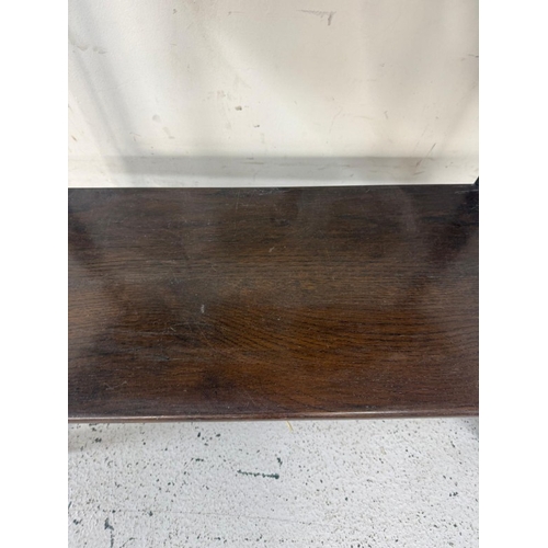 131 - An oak oval side table with shelves under H77cm W91cm D40cm