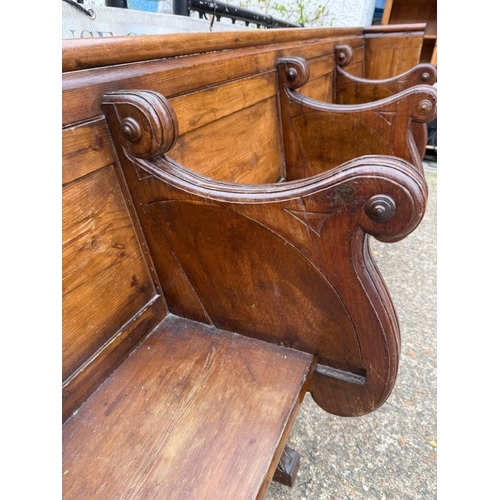 134 - An oak four seater church pew with gothic carved panels and scrolling arms H90cm W260cm D39cm