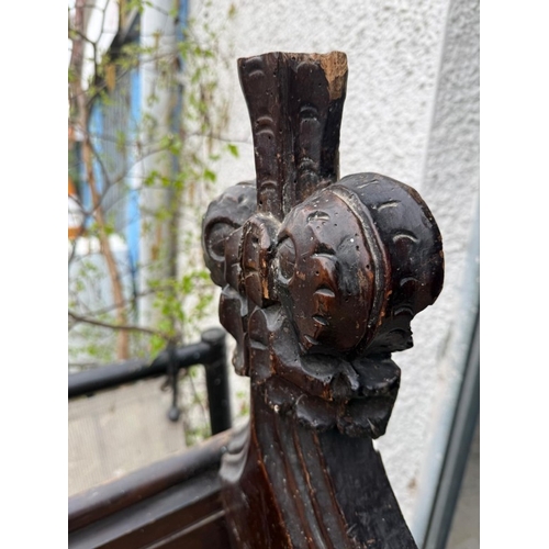 136 - An oak church pew with paneled back and carved ornamental ends H123cm W228cm D33cm