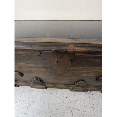 150 - A hardwood storage trunk with carved detail to the side and a glazed lid opening to a selection inte... 