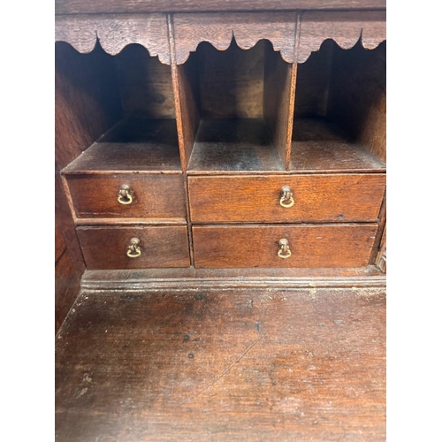 154 - An oak four drawer bureau with brass handles, the fall opening to pigeon holes and drawers H107cm W9... 