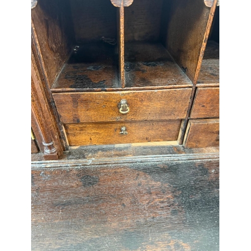 154 - An oak four drawer bureau with brass handles, the fall opening to pigeon holes and drawers H107cm W9... 