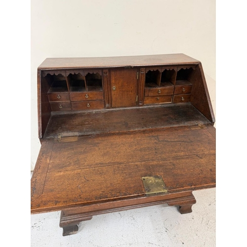 154 - An oak four drawer bureau with brass handles, the fall opening to pigeon holes and drawers H107cm W9... 