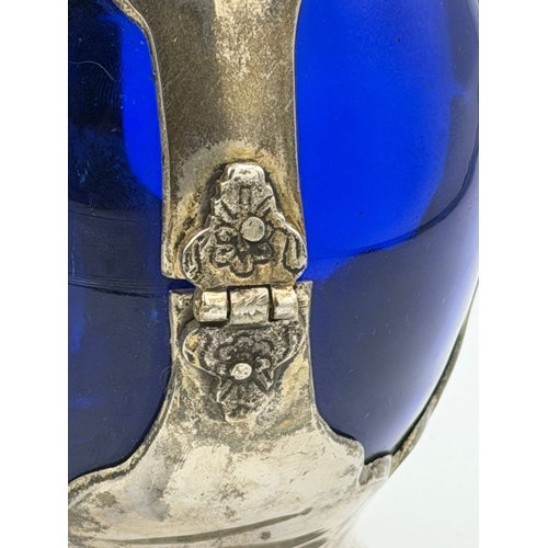 395 - An Art Nouveaux cobalt blue decanter encase in white metal with small glass screw top cup. Height ap... 