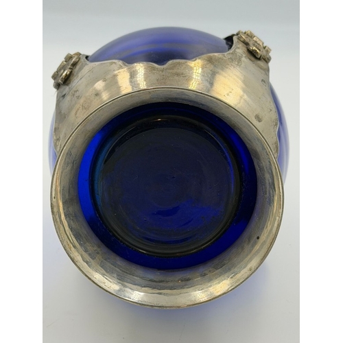 395 - An Art Nouveaux cobalt blue decanter encase in white metal with small glass screw top cup. Height ap... 