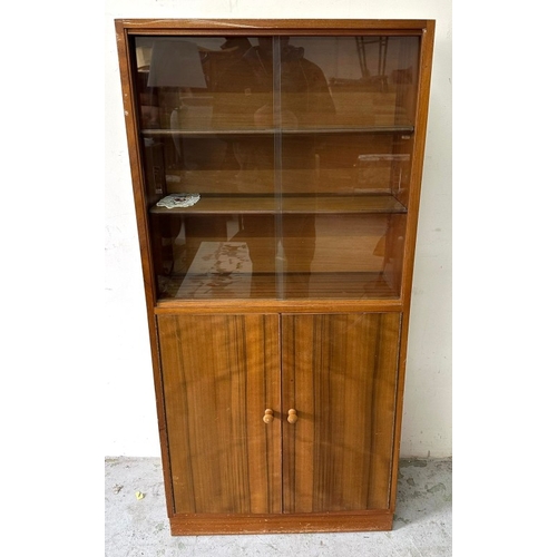 94 - A teak glazed bookcase with sliding doors over a two-door cupboard H145cm W69cm D28cm