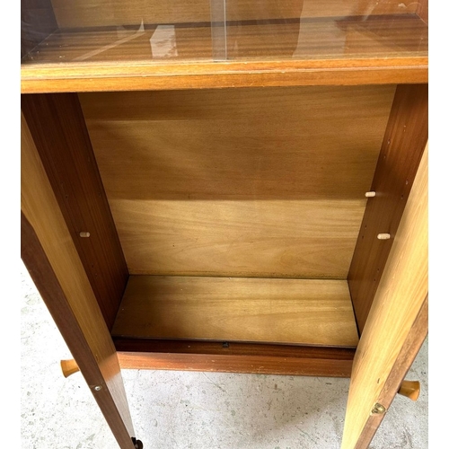 94 - A teak glazed bookcase with sliding doors over a two-door cupboard H145cm W69cm D28cm