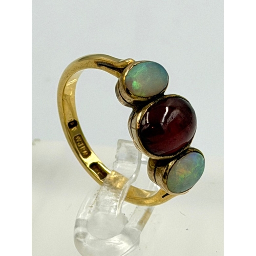 602 - A 22ct gold three stone ring with central garnet and two opals, approximate weight 4.5g and size P
