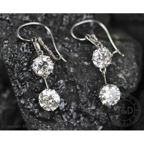 200 - A pair of two stone diamond set drop earrings, each designed as a claw set brilliant cut diamond, su... 