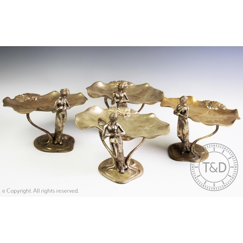 95 - A set of four silver plated Art Nouveau figural table centres, each modelled as raised twin lily pad... 